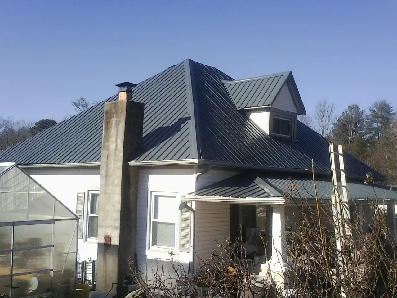 Dark blue standing seam metal roof on a white farmhouse with dormer — Slate & Tile Roof Repair by Roofing Brothers in Round Lake