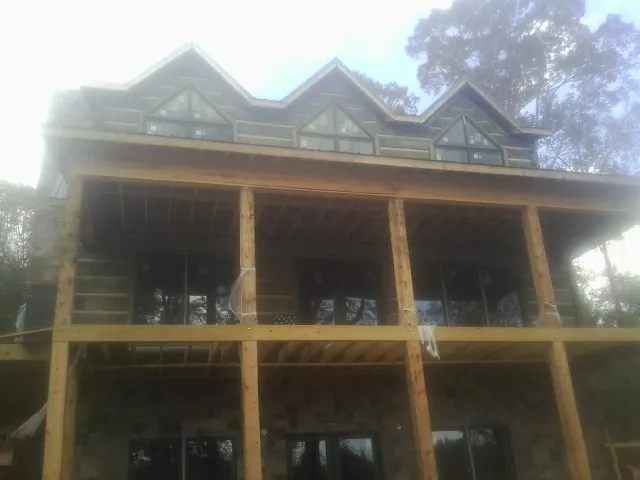 Dormers and porch framing on a large log home under construction — Roof Coating work by our crew in Round Lake