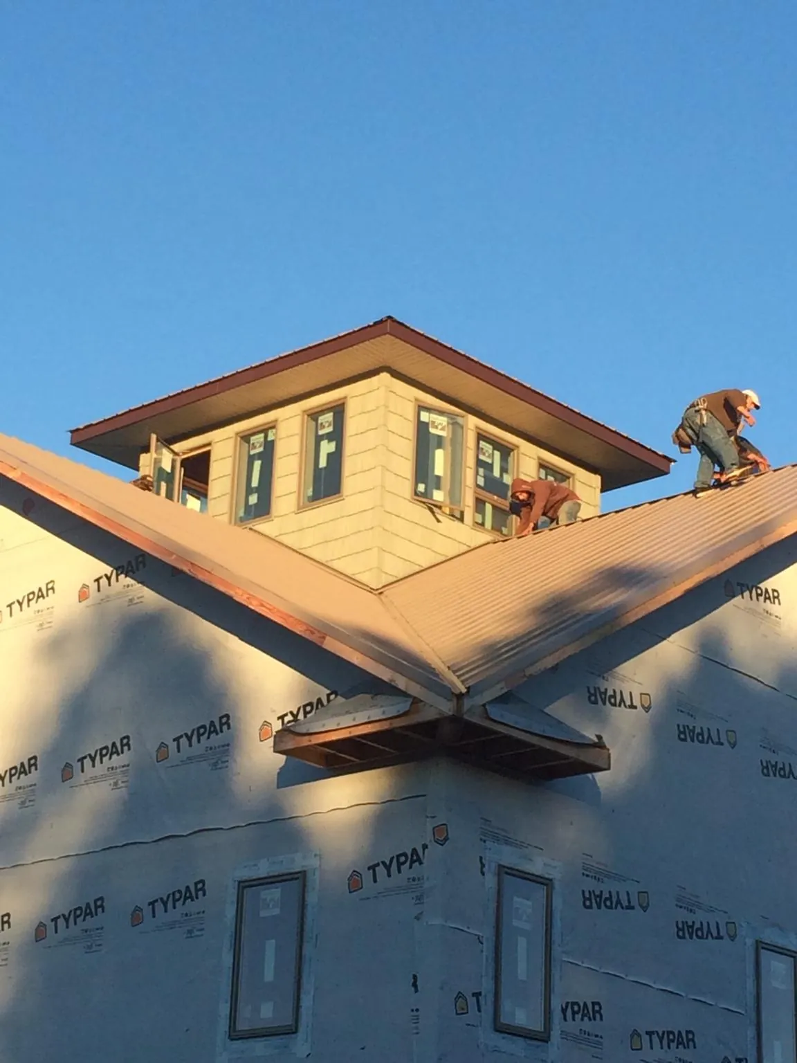 Roofers working around a rooftop cupola on a new metal roof at sunset — Roof Waterproofing in Round Lake by Roofing Brothers